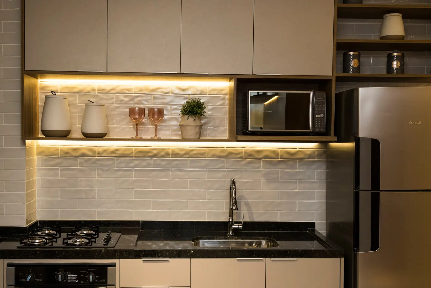 Cozinha planejada com marcenaria clara e iluminação sob os armários